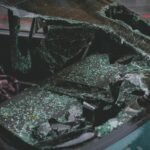 Vue détaillée du pare-brise d'une voiture brisée après un accident, mettant l'accent sur les dégâts et le verre brisé.