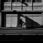 La silhouette d'un homme faisant du vélo devant un bâtiment dans la rue de la ville.