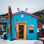 Une boutique bleue et jaune vibrante au milieu de la neige, parfaite pour les voyages et les thèmes hivernaux.