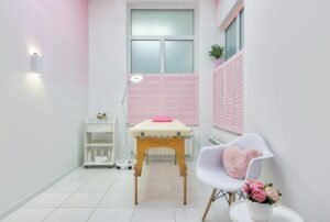 Conception créative d'un salon de massage avec une table entre les produits de beauté et un fauteuil contre des pivoines en fleurs dans un pot