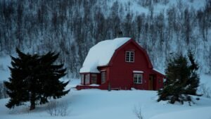 une maison rouge au milieu d'une forêt enneigée