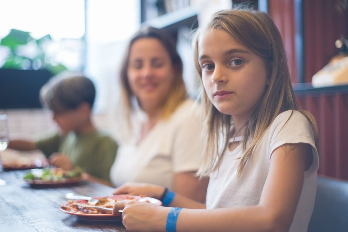 Jeune fille assise à table avec une assiette devant elle Jeune fille assise à table avec une assiette devant elle