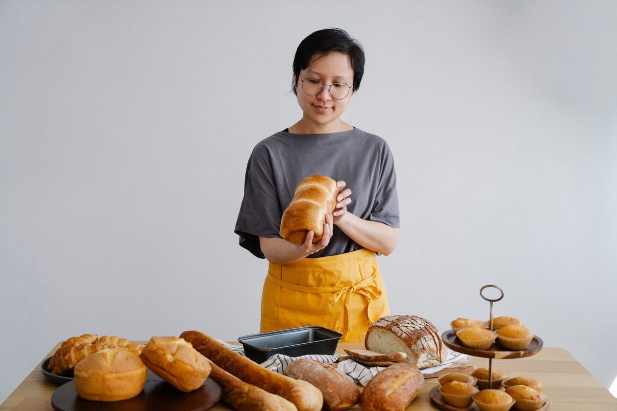 Femme avec pain devant une table de pâtisseries variées
