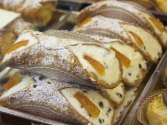 Des cannoli garnis de crème, zestes d'orange et raisins, saupoudrés de sucre